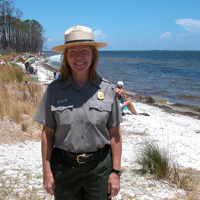 A female ranger stands in front of beach users at the Naval Live Oaks Area.