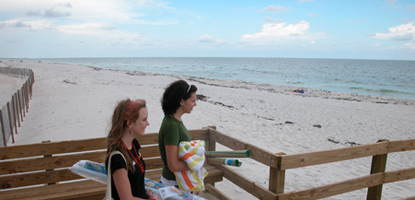 Wooded boardwalk over the white sand dunes leads to the blue waters of the Gulf of Mexico.