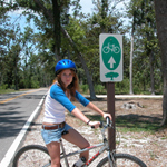 A female visitor on her bike is next to the Live Oaks Bicycle Route sign.