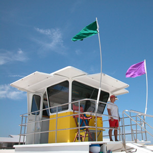 A national park lifeguard stands at the lifeguard tower while two safety flags fly in the wind.&nbsp;