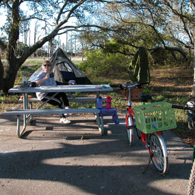 Woman sitting at a picnic table at her campsite.