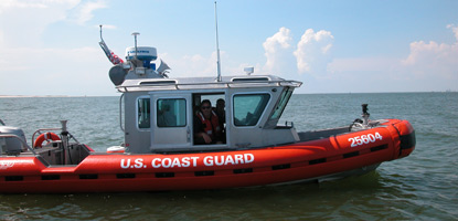 The bright orange U. S. Coast Guard vessel patrols the coastline.&nbsp;