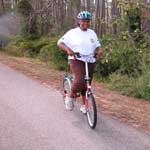 A female visitor  rides her bike on a paved bike path.