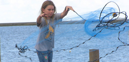 A young visitor expertly throws her 5 foot blue cast net, causing it to open in a perfect circle.