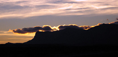 As the sun sets, the western sky behind the mountains is illuminated with color.