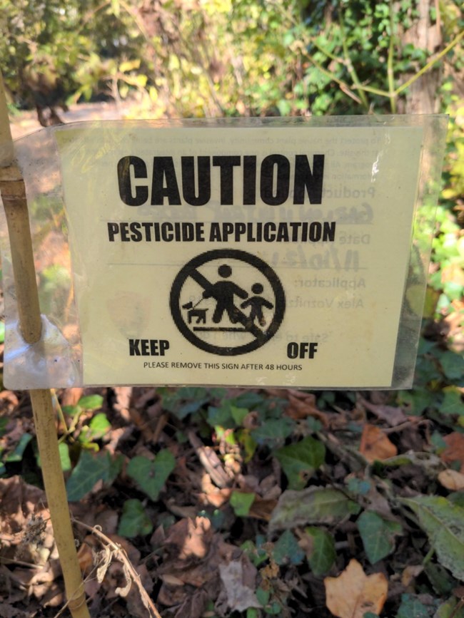 Yellow rectangular sign reads caution pesticide application