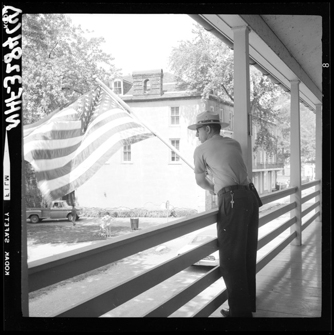 black and white photo of a ranger putting a flag out on a balcony