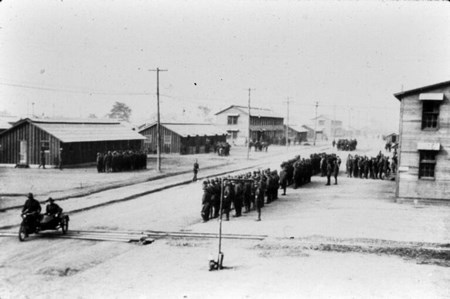 Soldiers standing at attention in front of camp buildings
