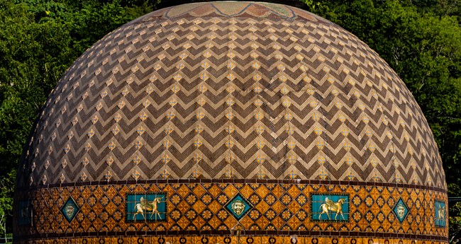 The dome roof of the Quapaw Bathhouse is an intricate pattern of mosaic tiles put together by hand. It has stripped tiles with flowers in between, leading to the top, with horses and lion faces surrounding the lower portion.
