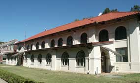 color photo of Hale Bathhouse from south end, a two-story Spanish style building with off-white stucco walls and red tile roof