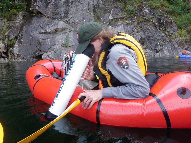 National Park Service scientist in a raft using a scope to see under water