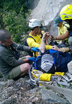 Hiking lying in litter with rescuers providing care