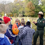 Park Ranger standing in front of students next to a farm field