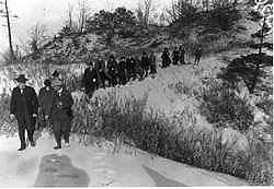 black and white picture from 1916 showing people walking down off a sand dune