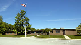 one story office building with flag pole and parking lot in front one story office building with flag pole and parking lot in front