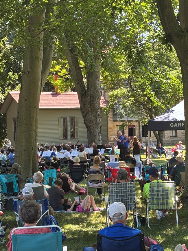 A band plays outside on a lawn to an audience