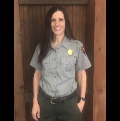 woman with long brown hair is wearing the National Park Service uniform