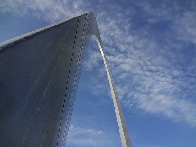 Looking up at the curve of the Gateway Arch against a blue sky