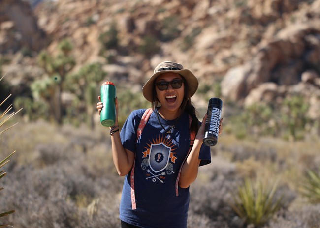 A happy hiker holding two water bottles