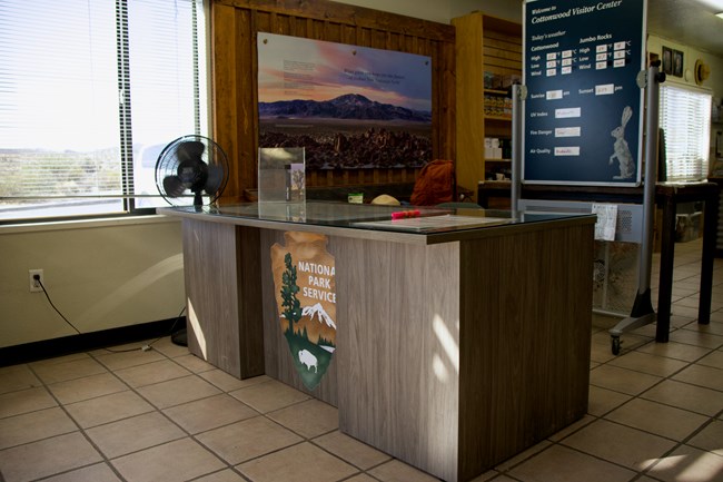 A lowered desk with the NPS Arrowhead in a visitor center