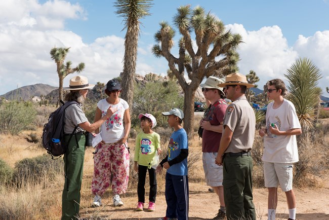 Two park rangers talk to visitors outside