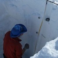 Park scientist measure the year's snow accumulation in an ice pit.