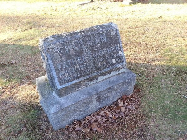 A grave marker in a cemetery that has weathered much of the text.