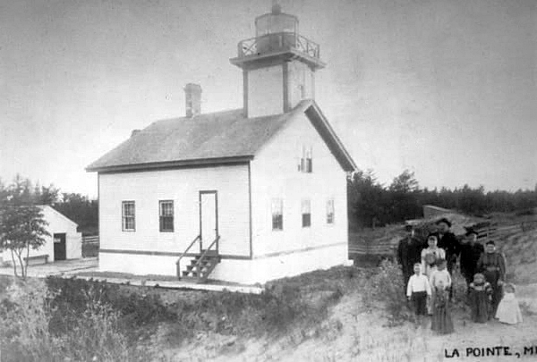 Old LaPointe Lighthouse with a group of people standing in front of it.