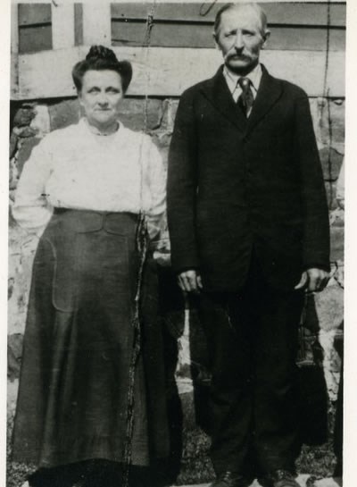 A man and woman pose for a photograph while standing in front of a building.