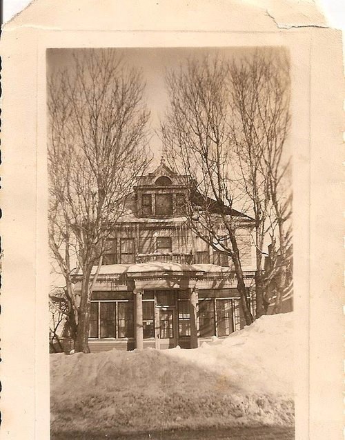 The front of a two-story house with snow in front of it.