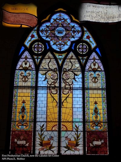 A large stained glass window is multi-colored with different flower and plant depictions.