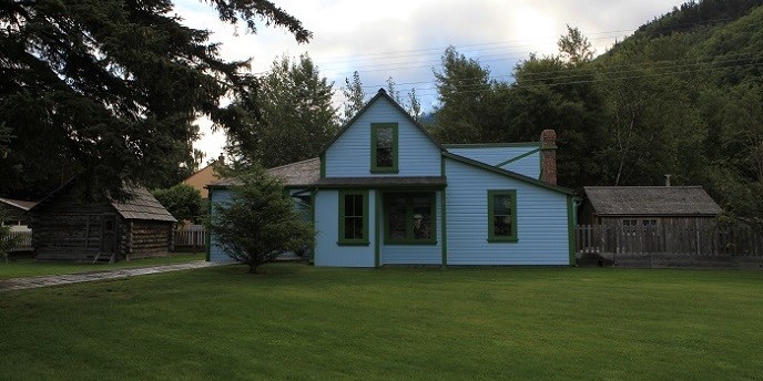 Una casa azul y una cabana con un jardin verde
