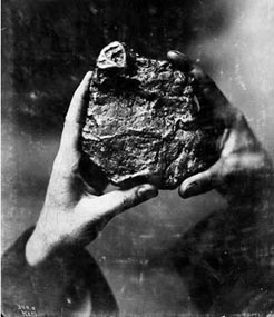 View of someone holding a gold nugget nearly the size of a cantelope.