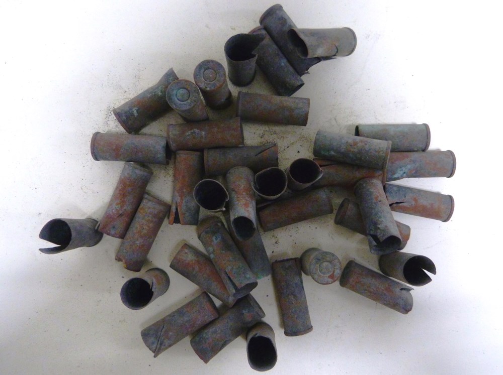 Multiple rusted metal cylinders with one closed end forming empty ammunition cartridges