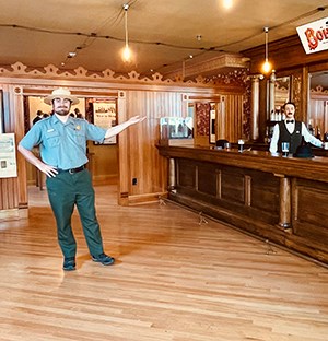 A ranger stands inside the Mascot Saloon with his arm outstreched.