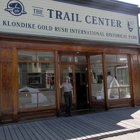 Building with large windows and sign reading "The Trail Center" with a ranger in front.