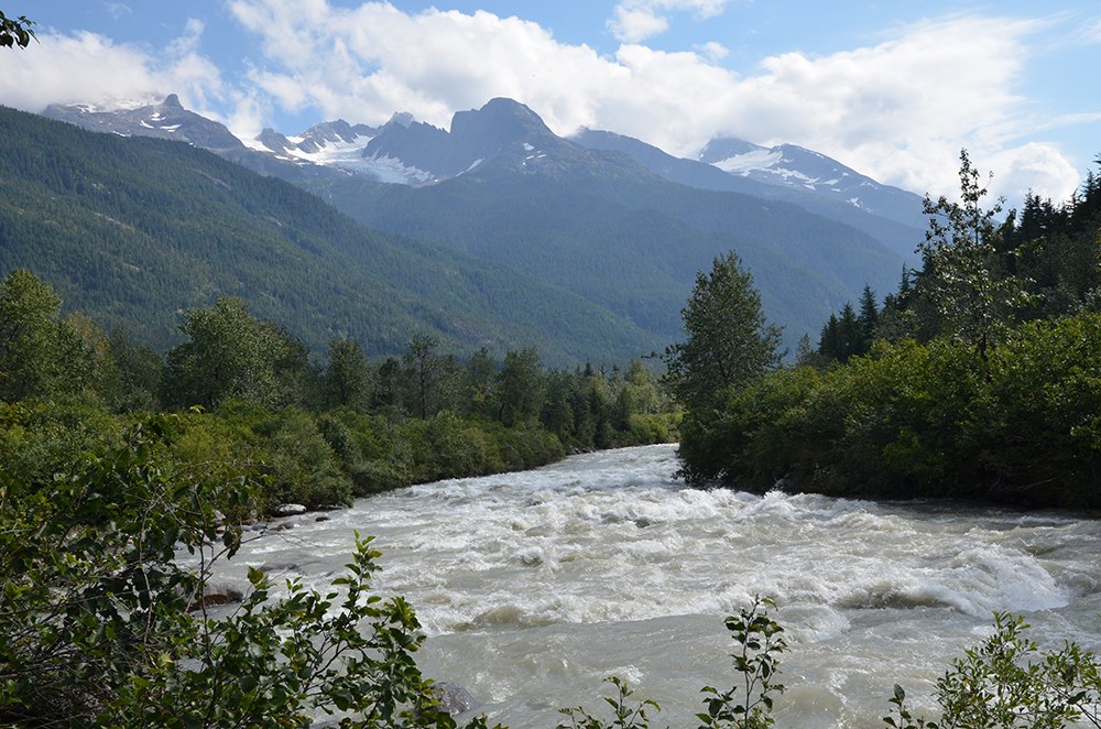 A silty river with mountains and glaciers in the background.