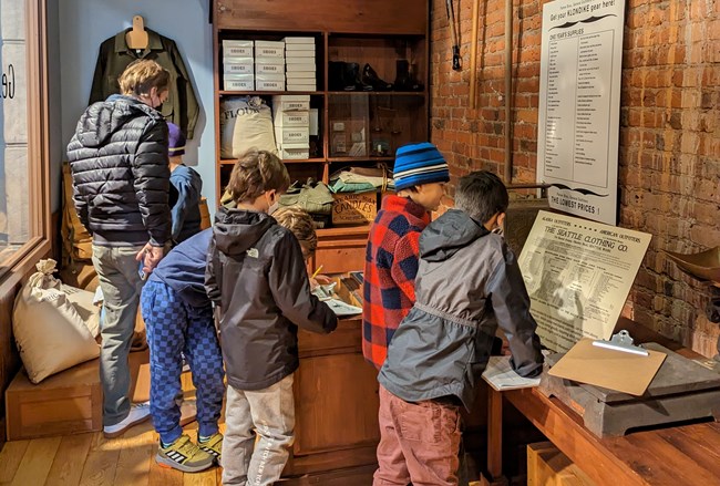 Five children and an adult explore the interior of a historic store.