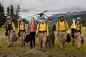 eight people walking away from a helicopter