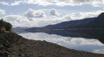 Lake smooth like glass. Clouds in a blue sky reflected on the lake.