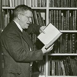 Man standing in front of bookshelf with book in hands