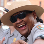 A young male ranger laughs while pointing at the camera