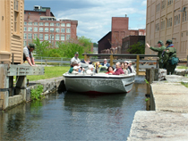 Lowell National Historical Park canal boat passes through Swamp Locks in downtown Lowell, MA Lowell National Historical Park canal boat passes through Swamp Locks in downtown Lowell, MA