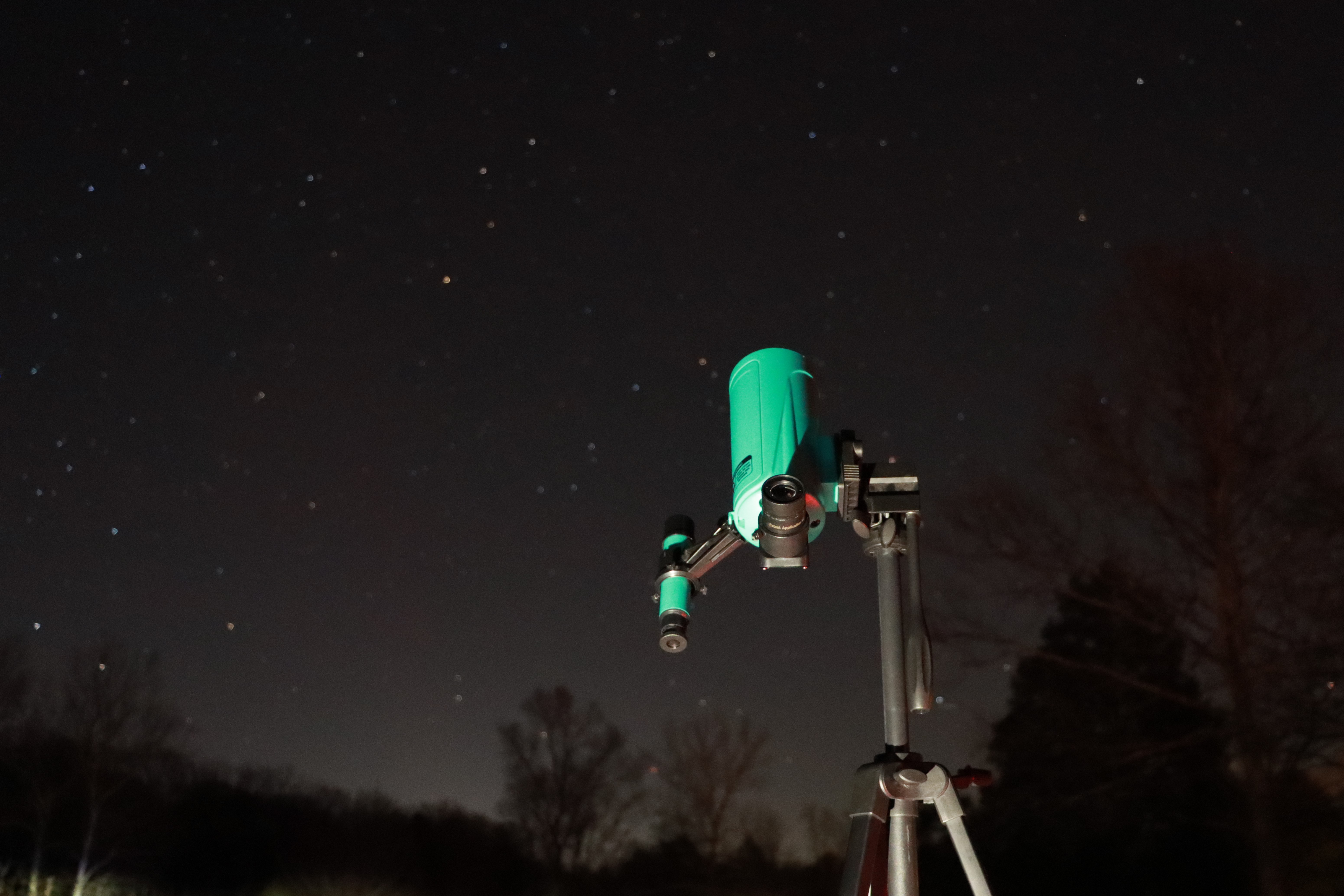 A green telescope against a background of the starry night sky