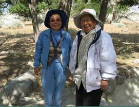 Two smiling women stand in the remnants of the Block 22 garden.