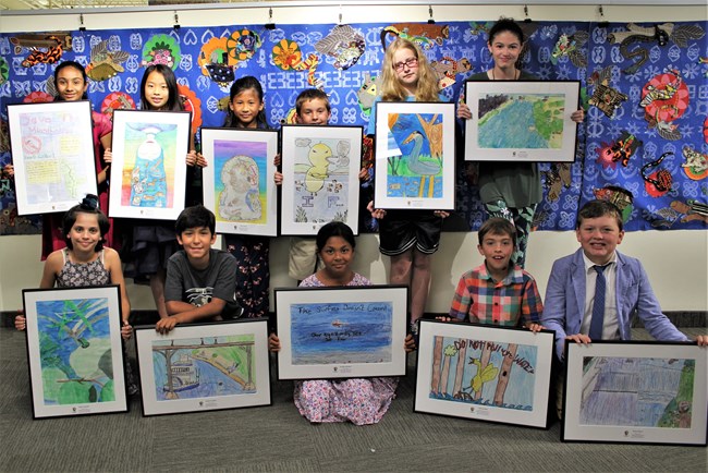 A picture taken of students holding up paintings.