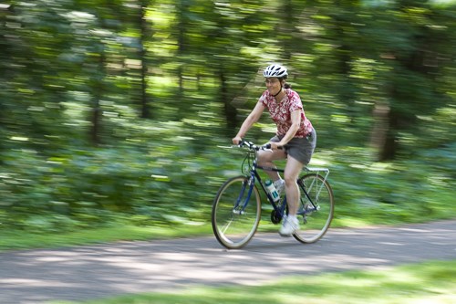 A woman rides a bike through a trail in the forest.