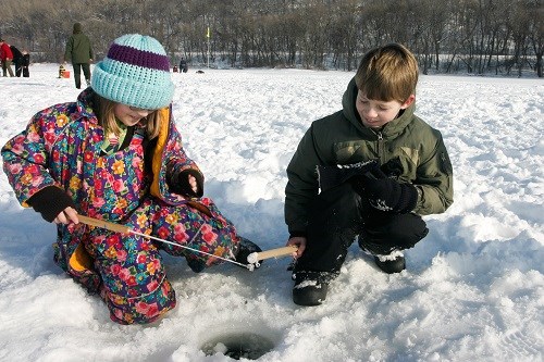 Two children fishing through the ice.