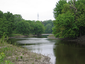 A river channel curves gently past wooded river banks.