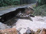 Water flows beneath missing section of road.